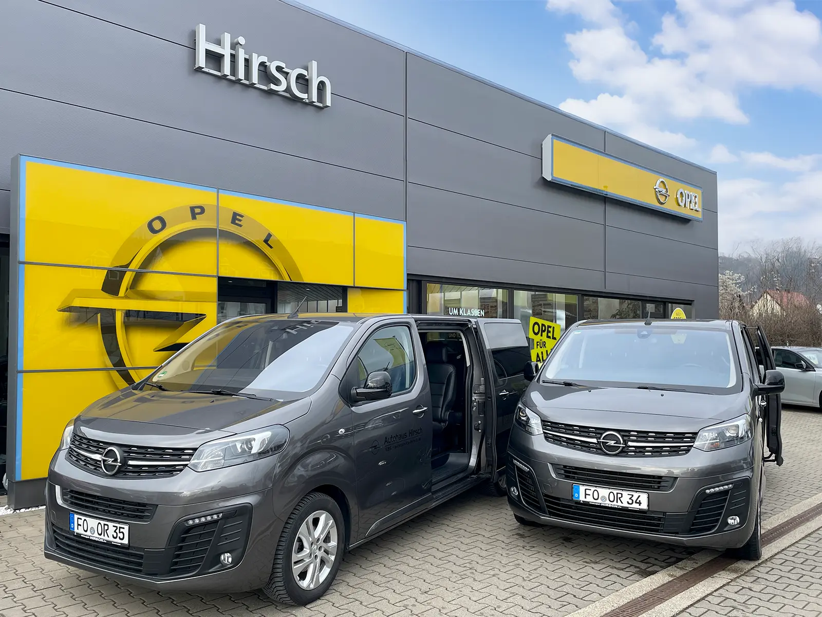 Hirasch Autohaus mit zwei Wagen davor, präsentiert mit offenen Türen